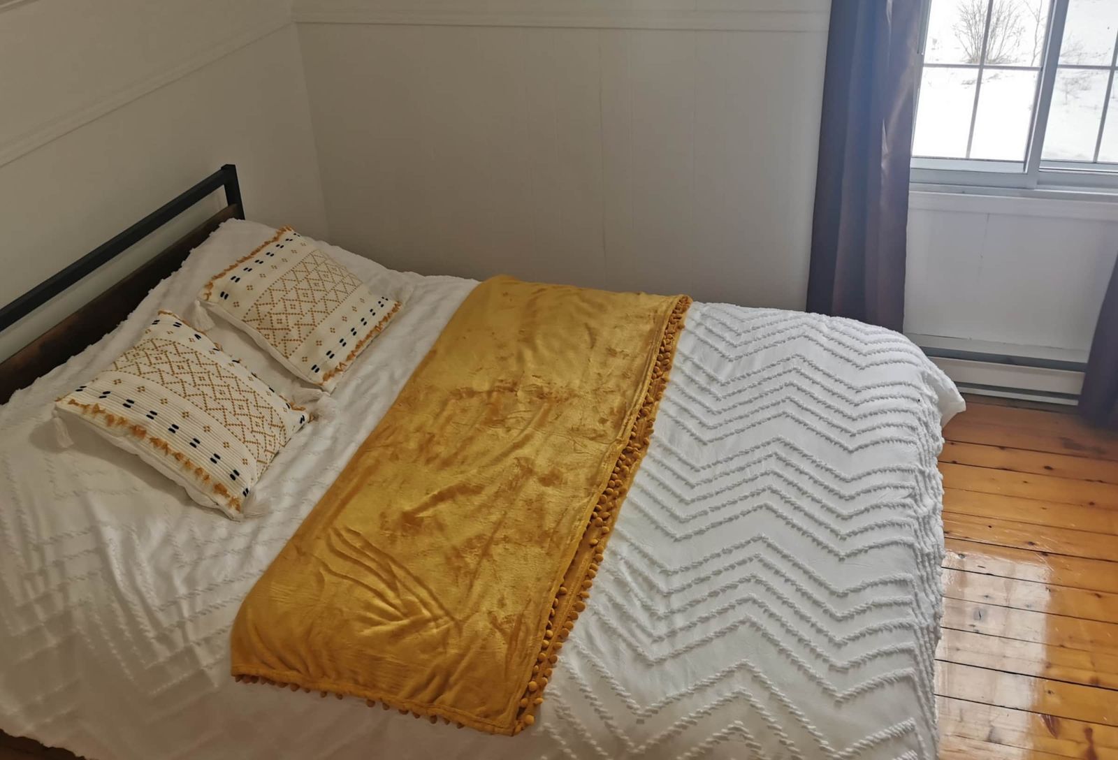 Chambre avec lit double et couvre-lit moutarde