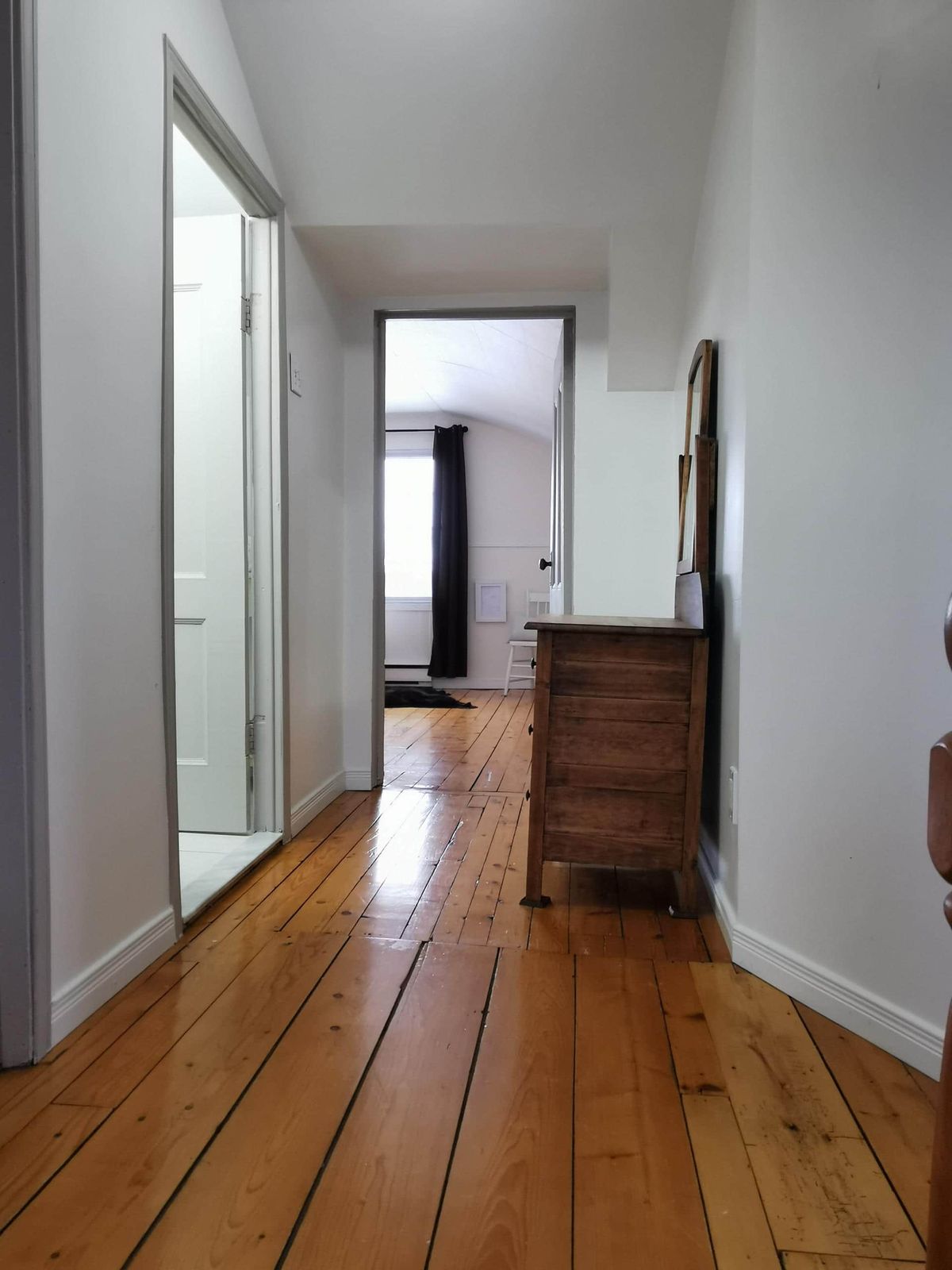 Couloir de l'étage avec commode ancienne et plancher pin