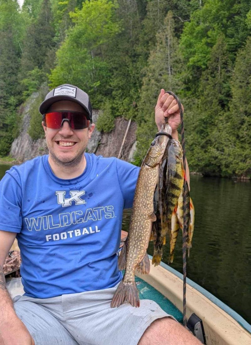 Pêcheur souriant tenant un brochet et des perchaudes pêchés au lac privé